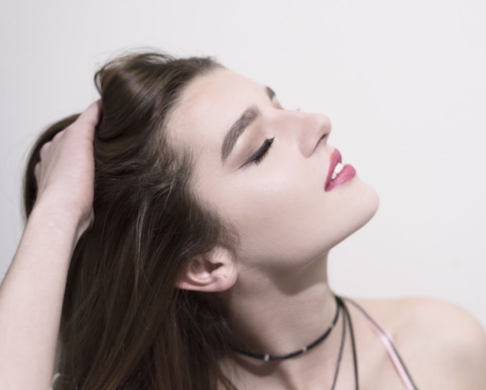 Longs cheveux bruns, tête inclinée en arrière, main dans les cheveux